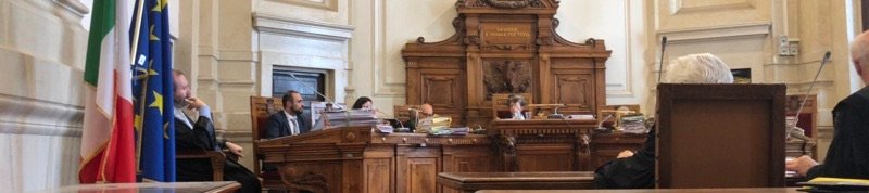 Aula d'udienza con le bandiere italiana ed europea e il banco del giudice