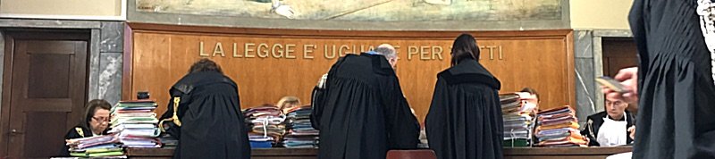 Avvocati in toga al banco del giudice, fra i fascicoli di causa
